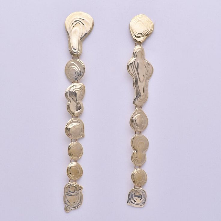 Lange Tropfohrringe aus Messing mit Stiften und Verstärkungen aus Sterlingsilber. Wie eine Kette aus goldenen Wassertropfen. 
Handgefertigt in unserem Studio in Los Angeles.
Details:
-Linker Ohrring ist 5 1/8" hoch.
-Rechter Ohrring ist 4 7/8" hoch.
-Tropfen baumeln an Messingösen für Bewegung.
-Messing mit Sterlingsilberpfosten und Butterfly-Rückseiten.