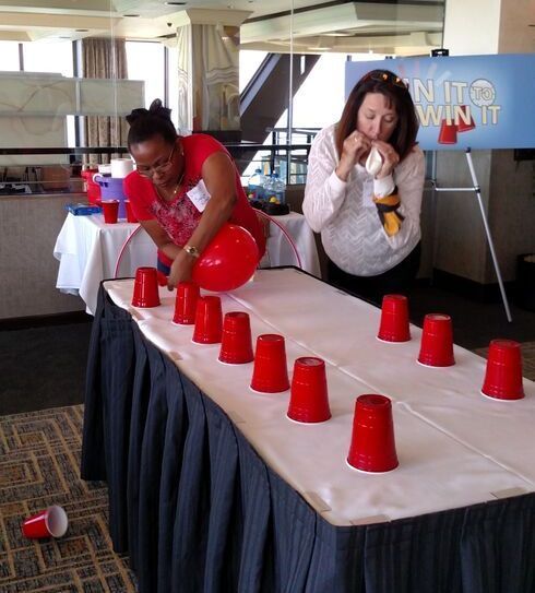 two women standing over a table with red cups on it