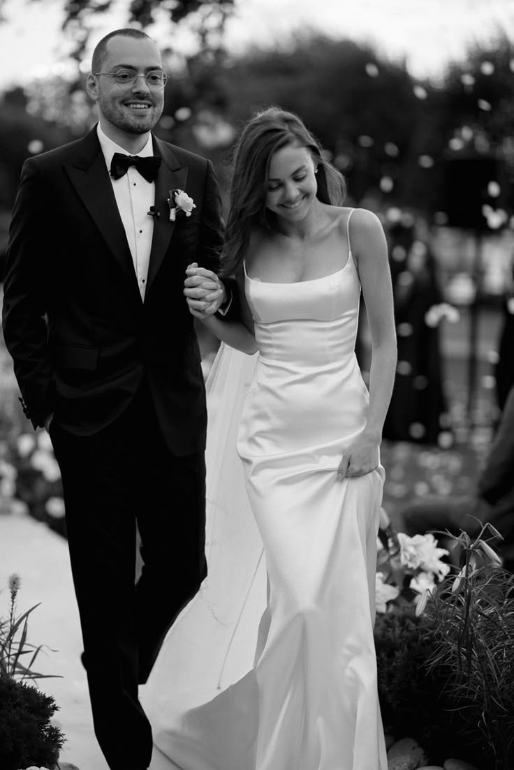 a bride and groom are walking down the aisle at their outdoor wedding in black and white