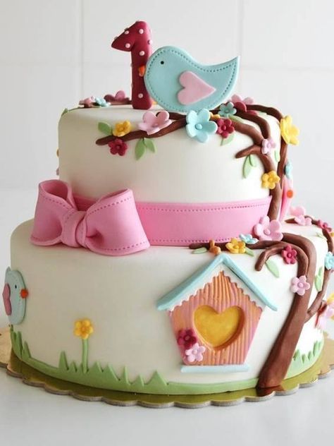 a three tiered cake decorated with birds, flowers and birdhouse on the top