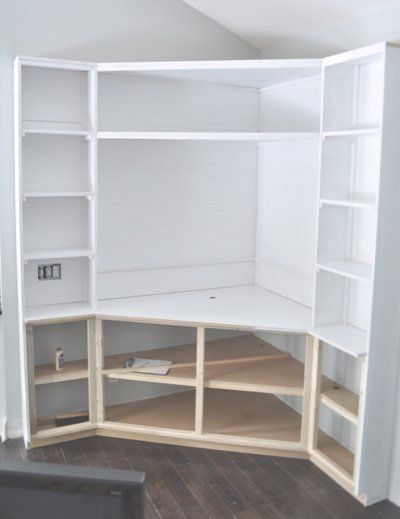 an empty white bookcase with shelves in the corner