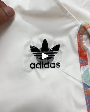 the adidas shirt is being held up by someone's hand