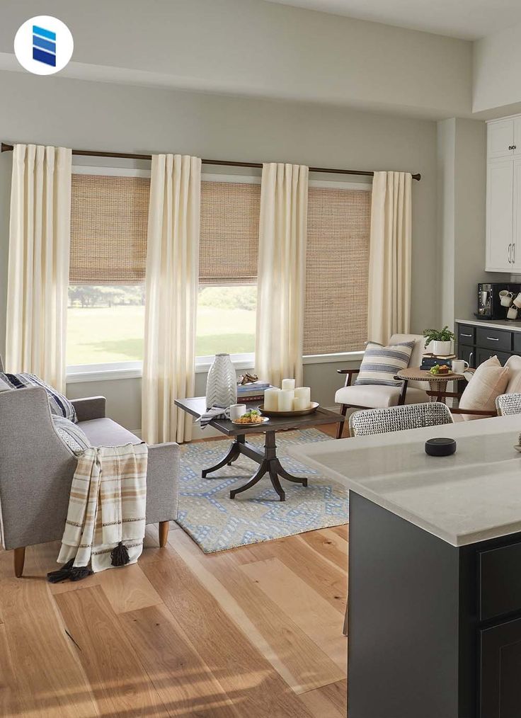 a living room filled with furniture and windows covered in shades of light brown, white and blue