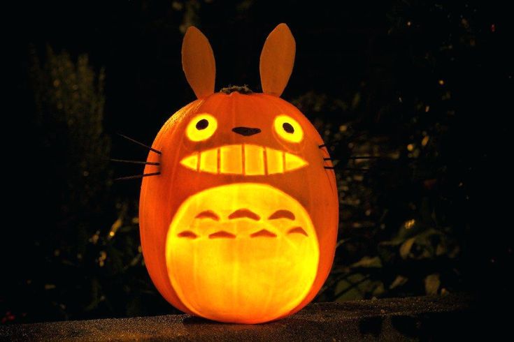 a carved pumpkin with an image of totoro on it's face in the dark