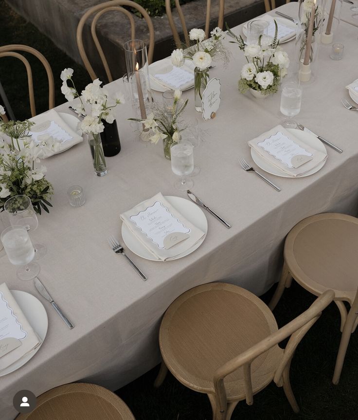 a long table with white flowers and place settings on it is set for an event