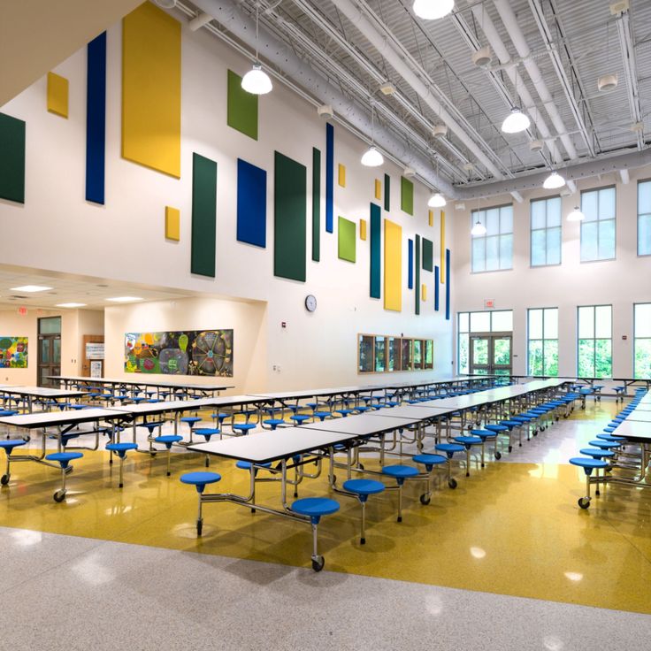 an empty cafeteria with tables and blue chairs