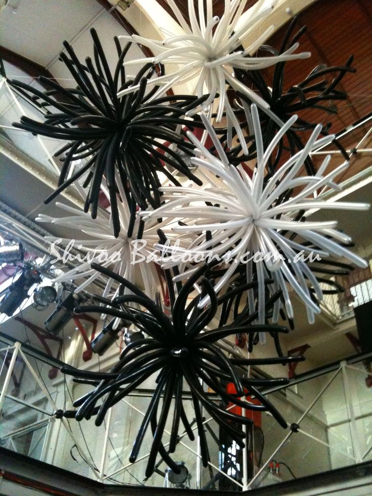 an artistic sculpture made out of black and white paper flowers hanging from the ceiling in a building