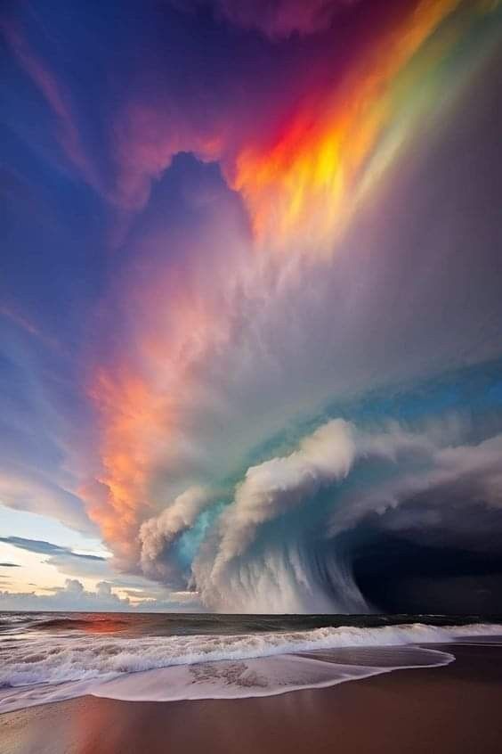 a colorful cloud formation over the ocean with waves coming in from the shore and on top of it