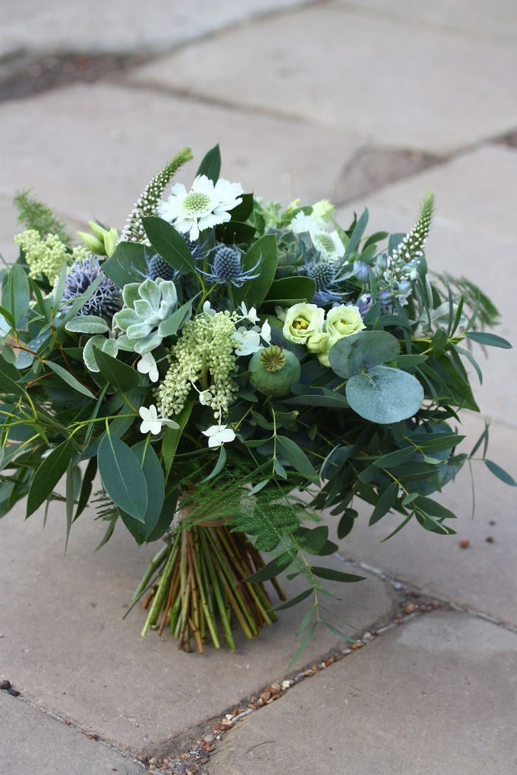 a bouquet of flowers on the ground with greenery and foliage in it's center