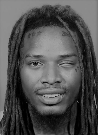 a man with dreadlocks is looking at the camera while wearing a white t - shirt