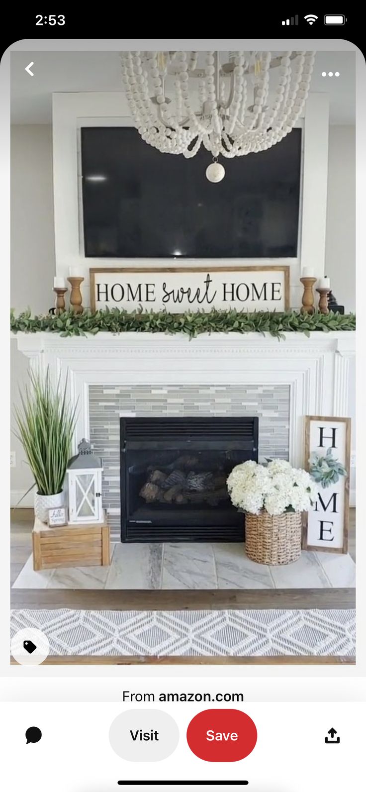 the fireplace is decorated with white flowers and greenery in front of a black tv