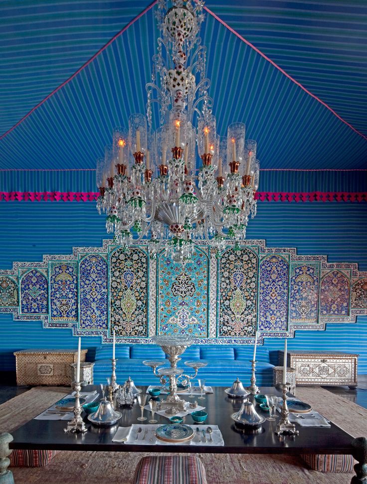 an ornate chandelier hangs from the ceiling in a dining room with blue walls