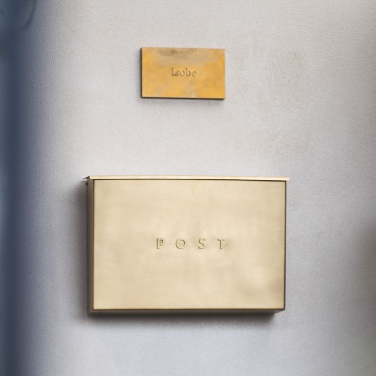 two gold plaques mounted to the side of a gray wall next to each other with writing on them