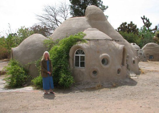 a woman standing in front of a house made out of rocks