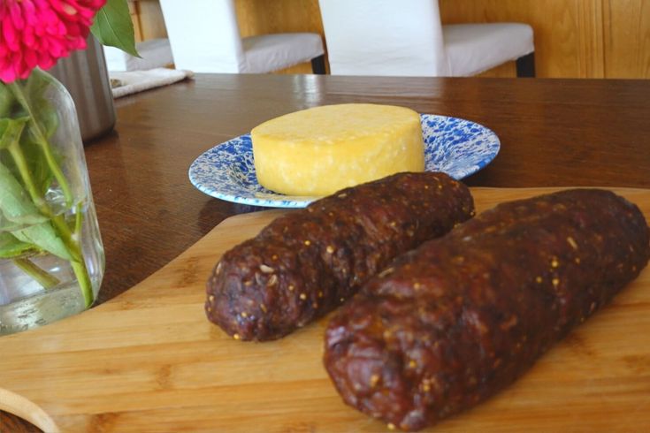 two sausages on a cutting board next to a vase with flowers