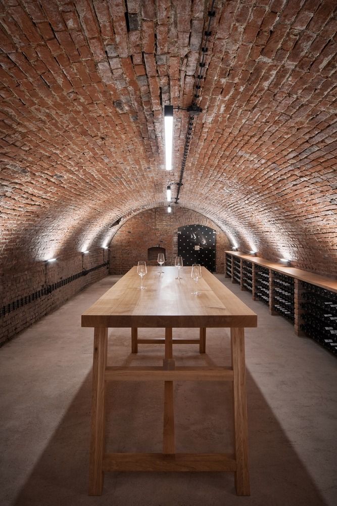 a long wooden table sitting in the middle of a room with lots of wine bottles