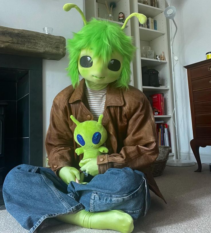 a person sitting on the floor with a stuffed animal in front of him and another doll behind them