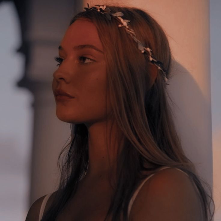 a woman with long hair wearing a flower headband and looking off into the distance