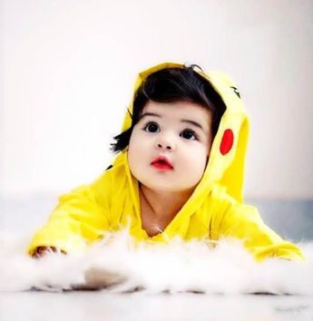 a young child in a yellow pokemon costume laying on the floor wearing a pikachu hoodie