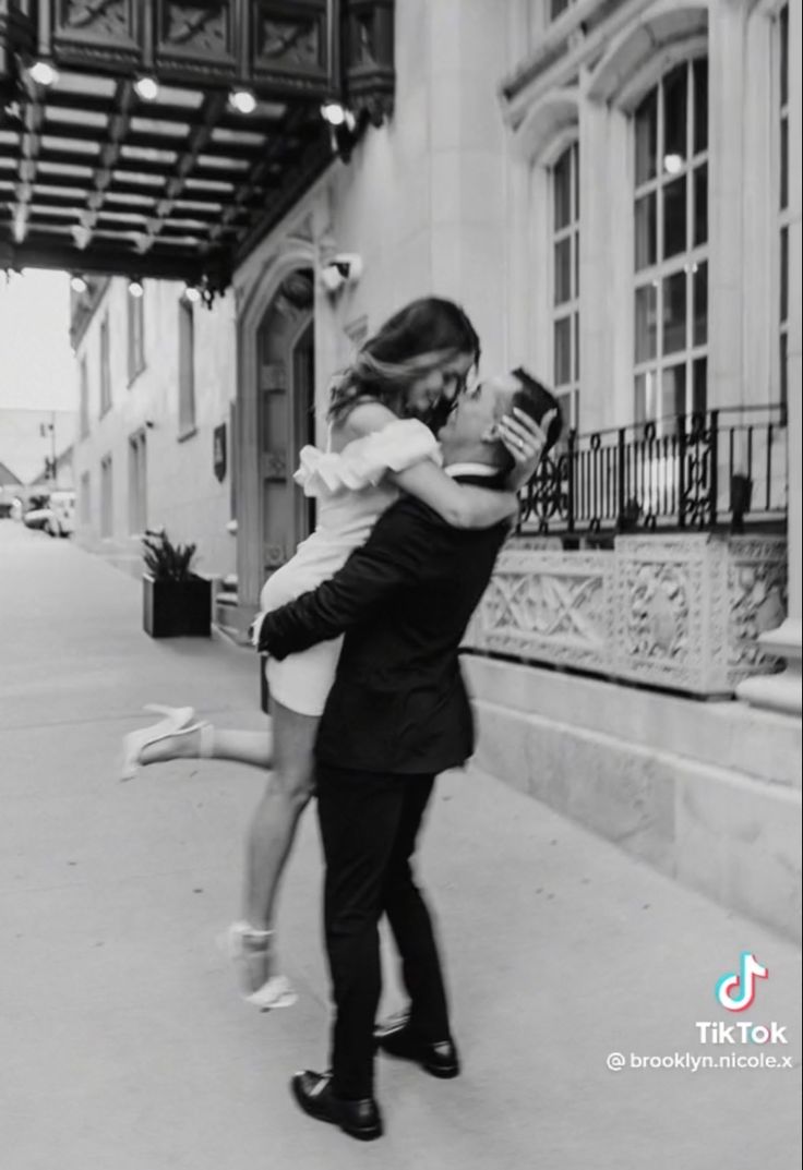 a man and woman are hugging on the sidewalk