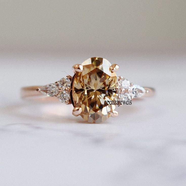 a fancy ring with an orange diamond and three white diamonds on the side, sitting on a marble surface