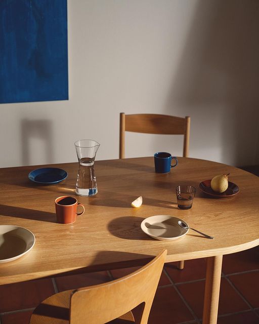 a wooden table topped with plates and cups