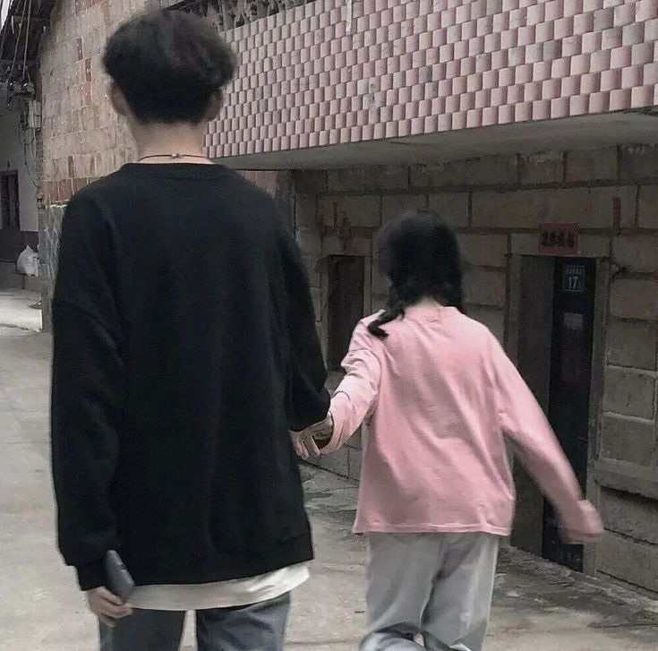 two people walking down the street with one holding the hand of another person's hand