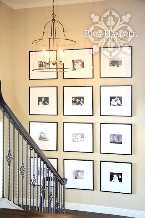 a staircase with pictures on the wall and chandelier hanging from it's handrail