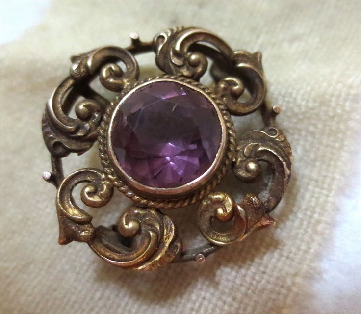 Antique Art Nouveau Gold and Amethyst Brooch or Pendant - 14 K Gold A swirled contrivance of Art Nouveau Design.. A small little jewel of a Pin.. of 14K Gold and discretely sized at 2 cm wide...like a delicate little button. Bezel set in the center, a large Amethyst rose-cut stone. The table is in very fine shape- with no scratches or wear. On the reverse, a simple , old fashioned C Clasp secures.. and a graceful sweep of wire forms the hidden means to string along a chain, that the piece might Purple Amethyst Gemstone Brooches, Antique Hallmarked Purple Brooches, Antique Purple Hallmarked Brooches, Unique Purple Brooch Jewelry, Purple Amethyst Brooches For Wedding, Purple Gemstone Brooches For Weddings, Purple Gemstone Wedding Brooches, Purple Gemstone Brooches For Gift, Victorian Jeweled Brooches For Gifts