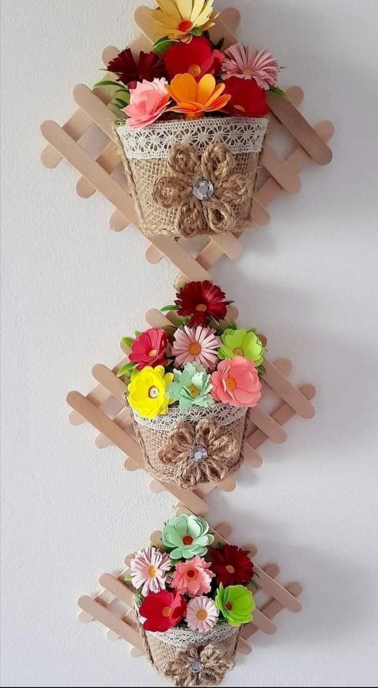 three baskets with flowers are hanging on the wall and one is made out of wood sticks