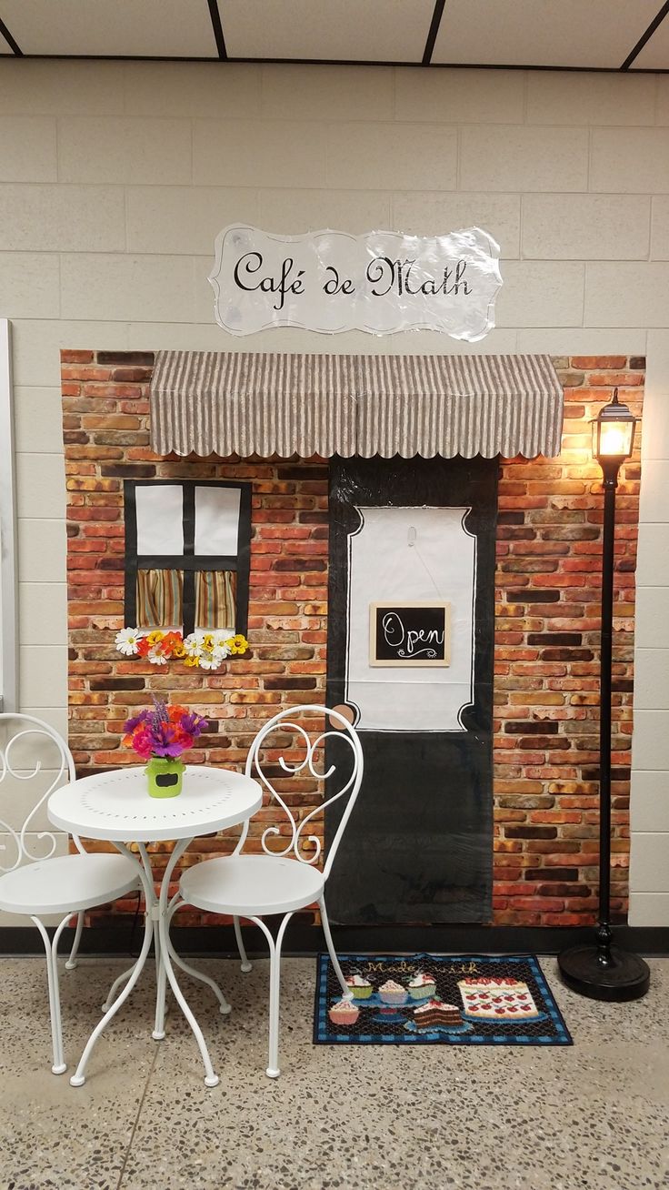 two white chairs and a table in front of a building with a sign that says cafe de math