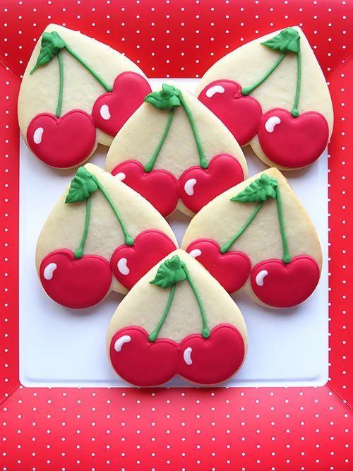 decorated cookies with cherries are on a plate