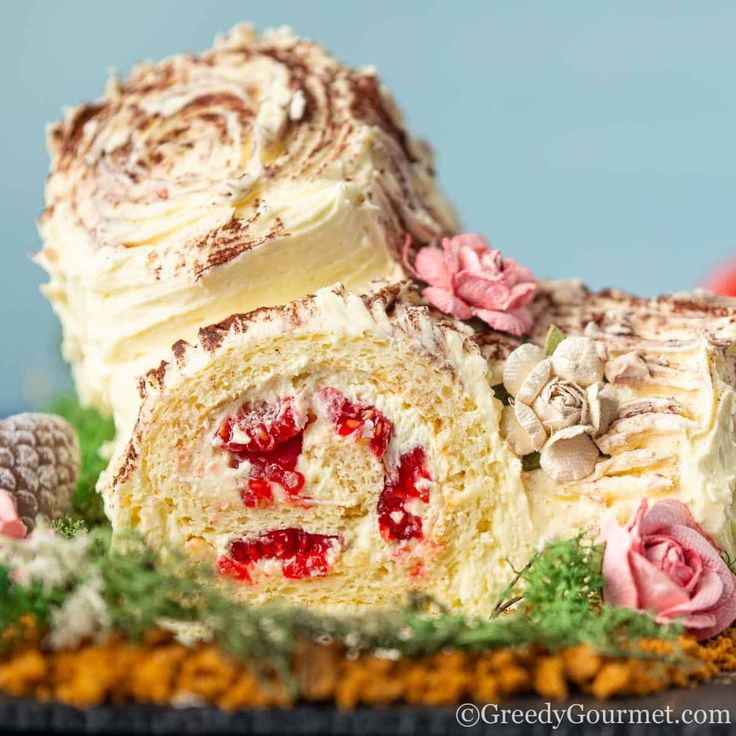 a close up of a cake roll on a plate with frosting and flowers around it