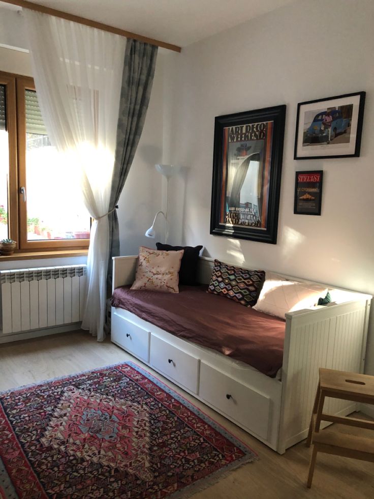 a living room with a couch, window and rug on the floor in front of it