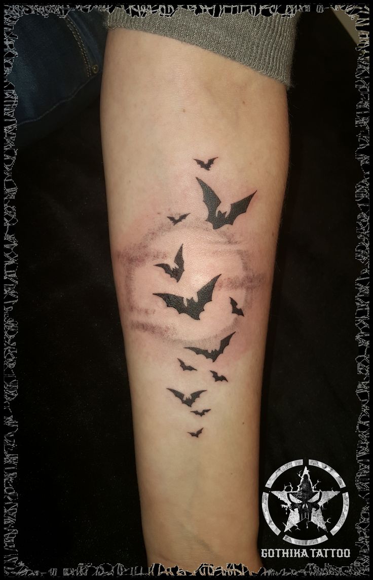 a person with a tattoo on their leg that has bats flying in the sky above them