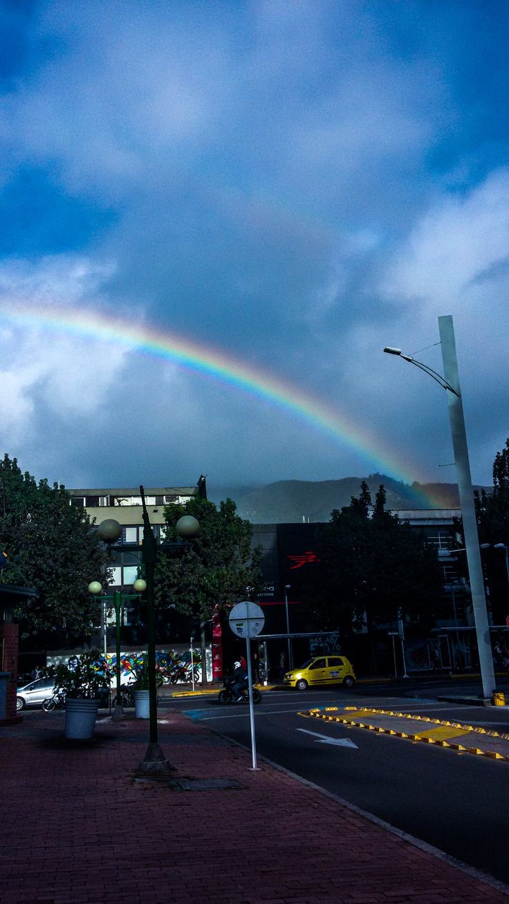 a rainbow shines in the sky over a city street