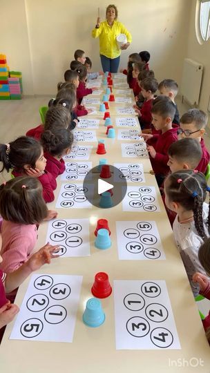 a group of children sitting at a table with paper cut out to spell out numbers