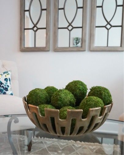 a bowl filled with green moss sitting on top of a glass table