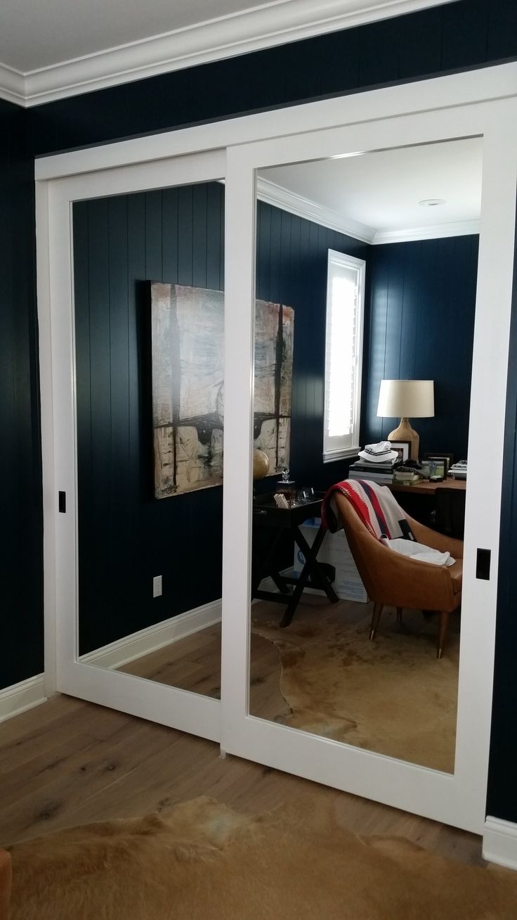 a living room with blue walls and white trim on the sliding glass doors that lead to an office