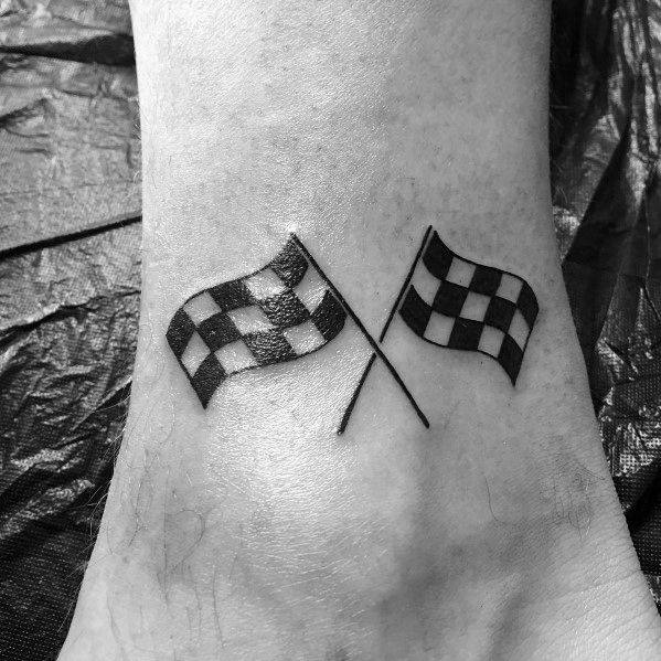 a black and white photo of a checkered flag tattoo on the left side of the foot