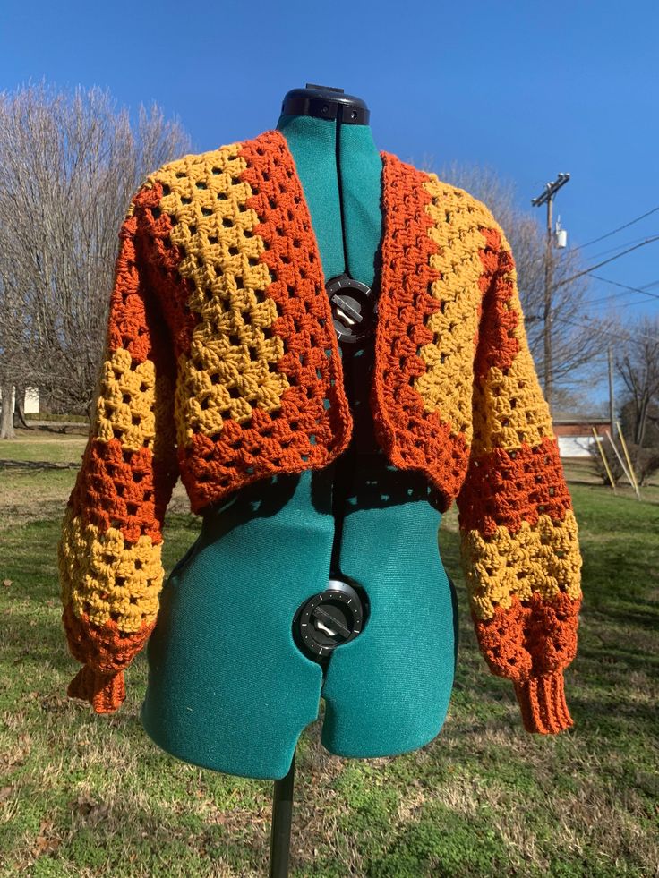 A fun cropped cardigan with an abstract color design! It features beautiful warm orange and yellow colors, chunky sleeves, ribbed cuffs to keep your hands free, and a mid-low waist length 🧡 This cardigan is tailored to fit Xtra Small, Small, Medium, and Large wearers best! Made with 100% acrylic yarn 🧶 Orange Crochet Outfit, Brown Cropped Sweater For Spring, Spring Brown Cropped Sweater, One Size Orange Long Sleeve Cardigan, Orange Long Sleeve One Size Cardigan, Retro Orange Spring Cardigan, Bohemian Long Sleeve Cropped Sweater For Fall, Multicolor Cropped Sweater For Winter, Winter Cropped Cotton Cardigan