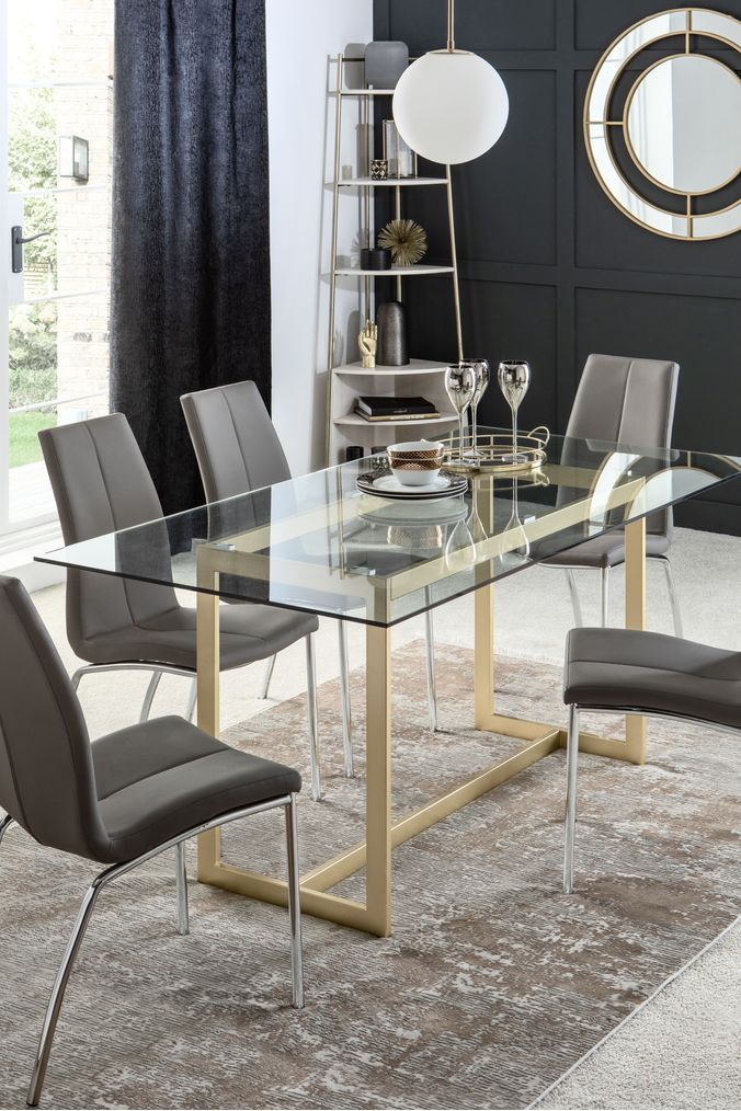 a glass dining table surrounded by grey chairs