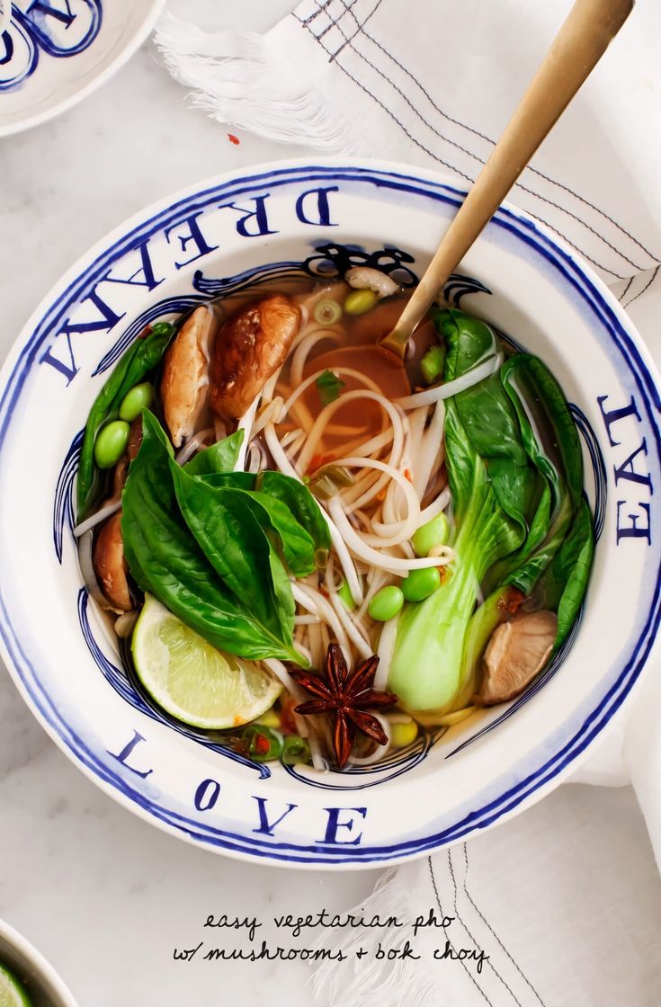 a bowl filled with noodles and vegetables on top of a white tablecloth covered table