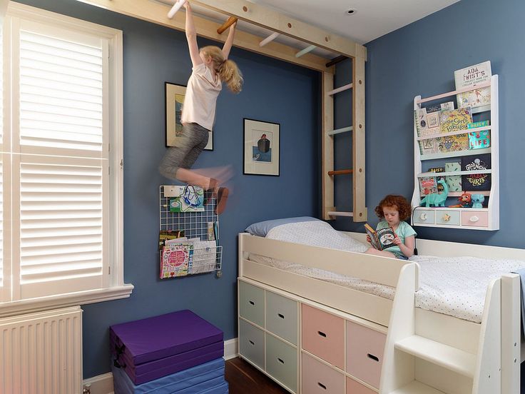 two children are playing on the bunk beds in this bedroom with blue walls and white shutters