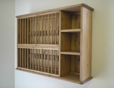 an old wooden shelf with bars on the bottom and shelves below it, against a white wall