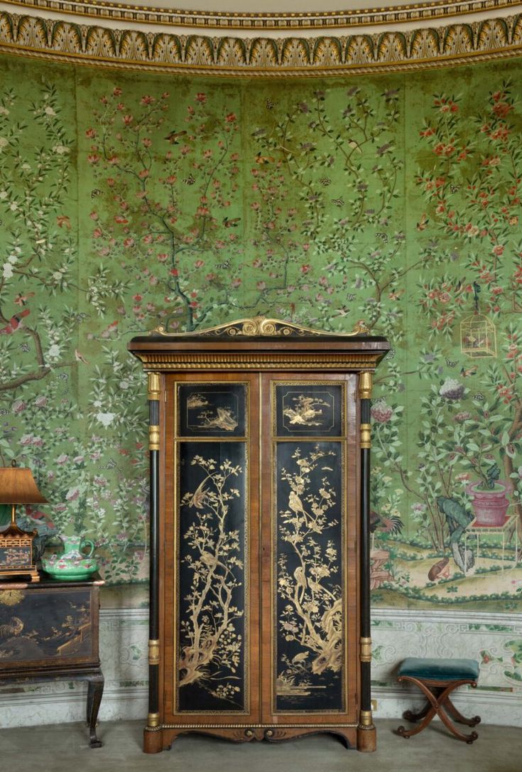 an ornate armoire in front of a wallpapered background