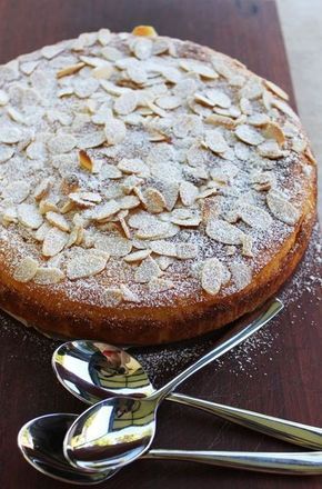 a cake sitting on top of a wooden table next to a fork and spoons