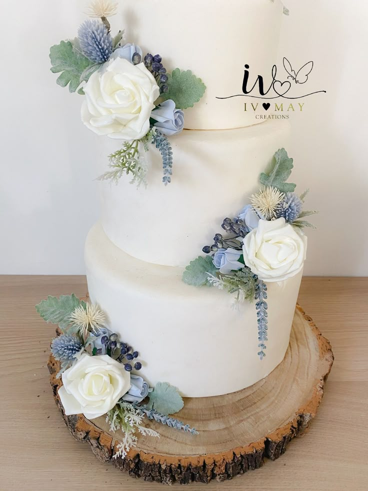 a white wedding cake with blue flowers and greenery