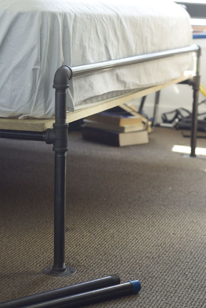 there is a bed that has been made with pipes on the floor and under it