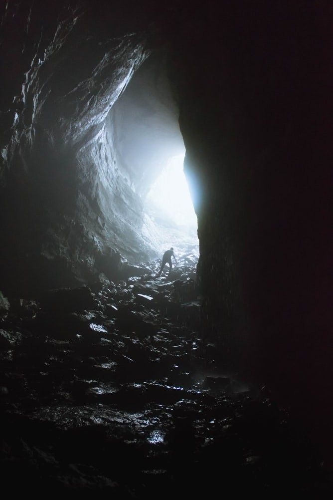 a man is standing in the light at the end of a cave